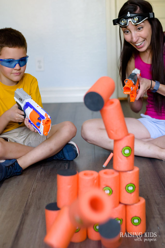 mom and son shooting tower of foam cylinders with NERF guns