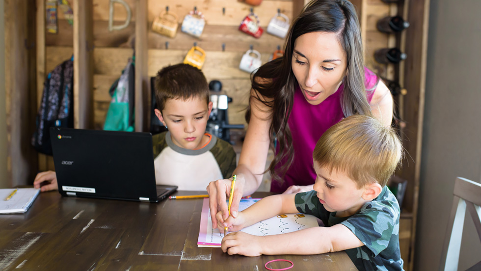 mom helping with boys at kitchen table to do homework