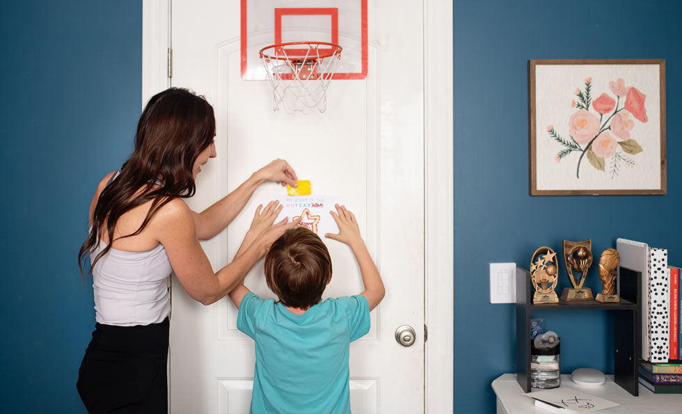 mom helping son hang word of the year poster