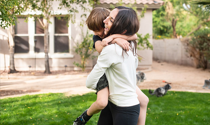 mom and son bear hugging in backyard