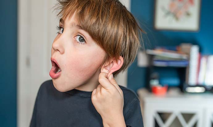 boy holding ear