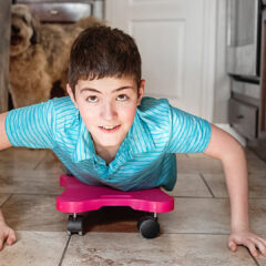 boy riding on a scooter board in kitchen