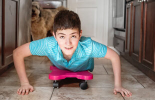 boy riding on a scooter board in kitchen