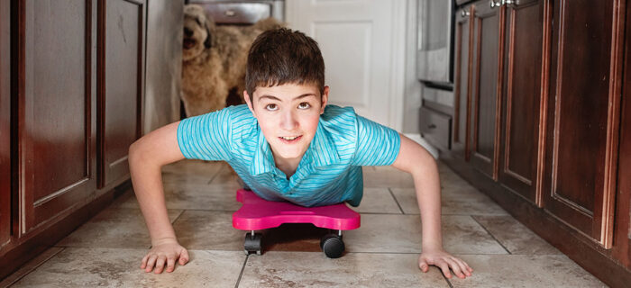 boy riding on a scooter board in kitchen