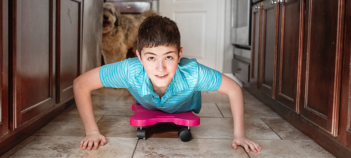 boy riding on a scooter board in kitchen