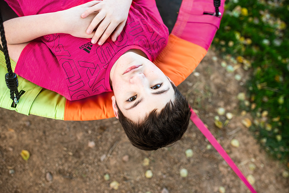 boy laying on a round swing in his backyard