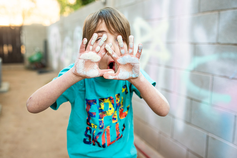 boy holding hands up in front of his face