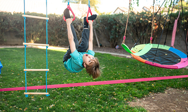 little boy upside down on a ninja slack line in Arizona backyard