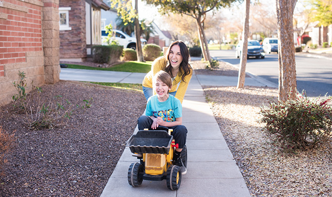 mom pushing son on tractor down street