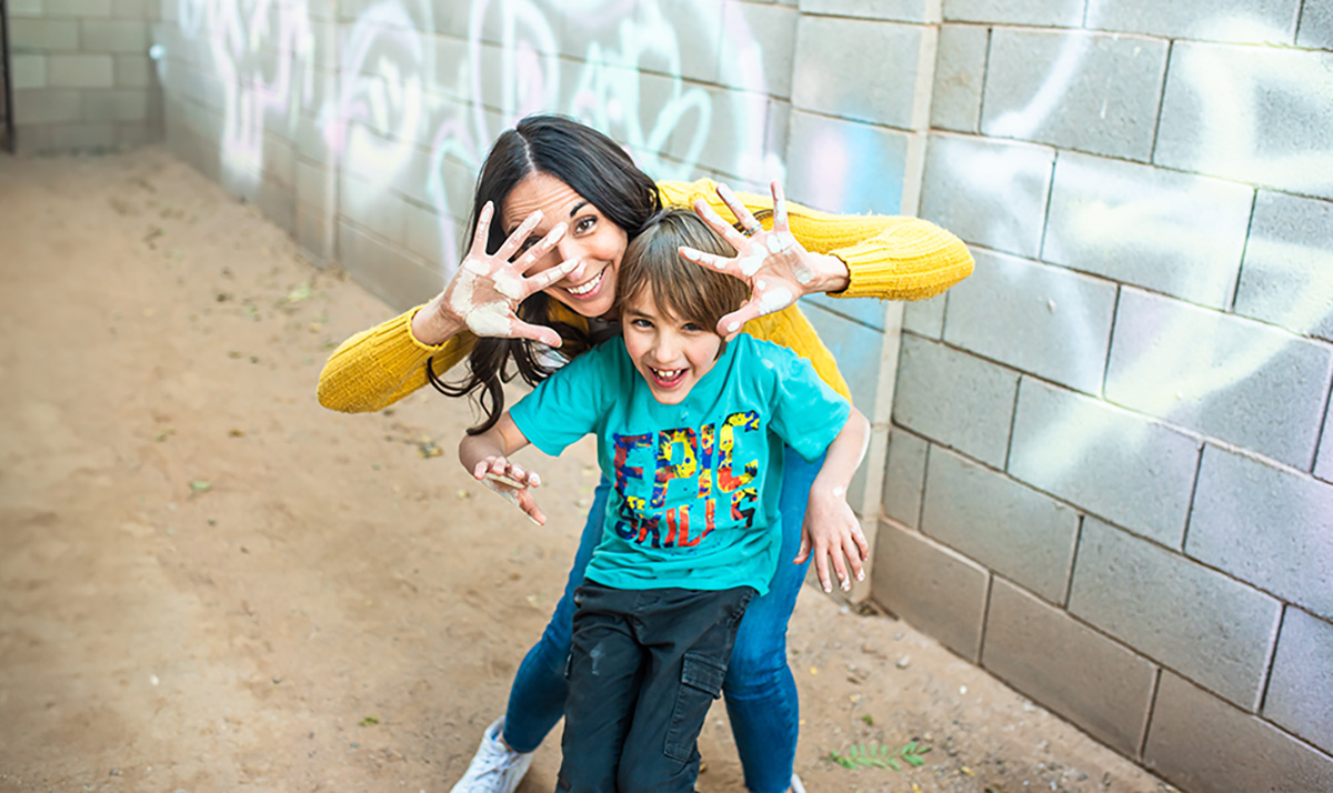 mom and son showing chalk hands with graffiti behind them