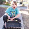 crazy kid riding digger toy down the sidewalk