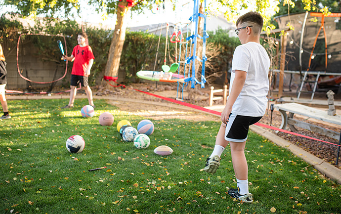 boys outside playing with balls and swords