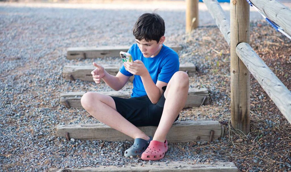 boy sitting on steps at KOA on a cell phone